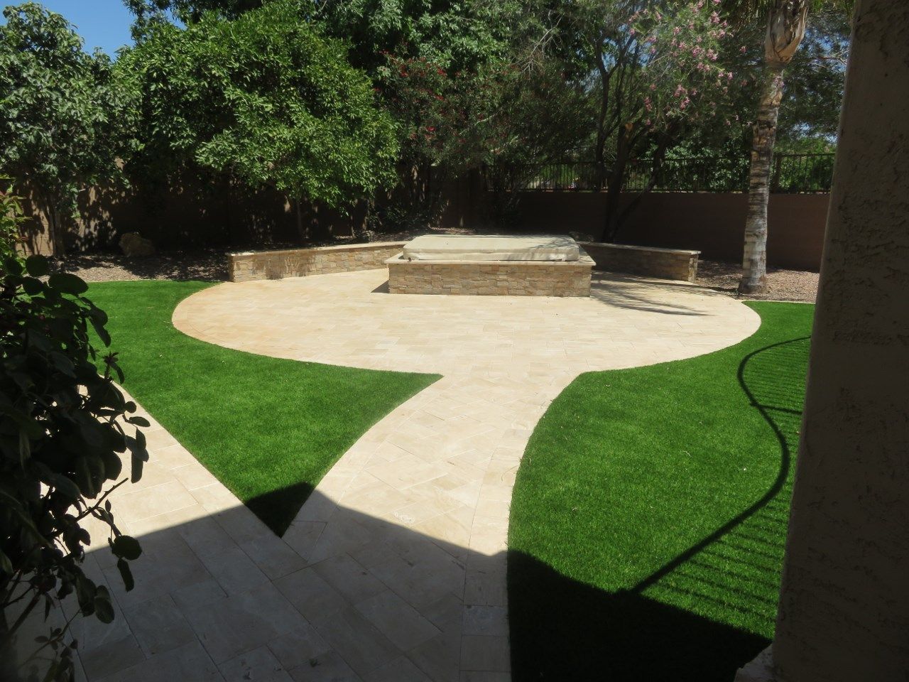 A backyard with a walkway leading to a hot tub