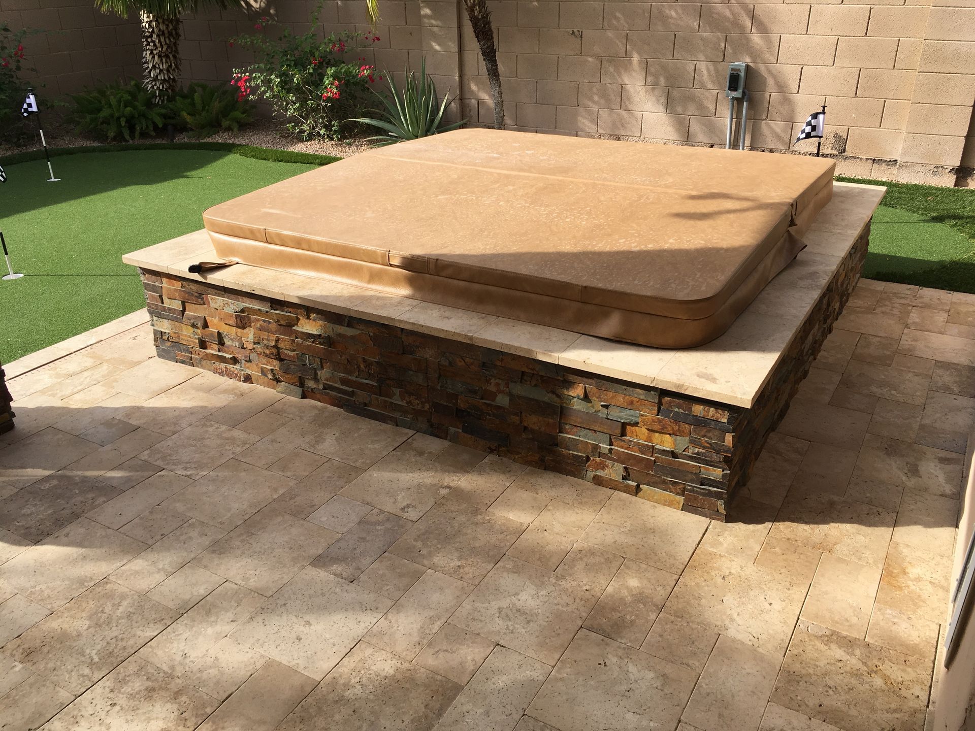 A hot tub is sitting on top of a stone patio.