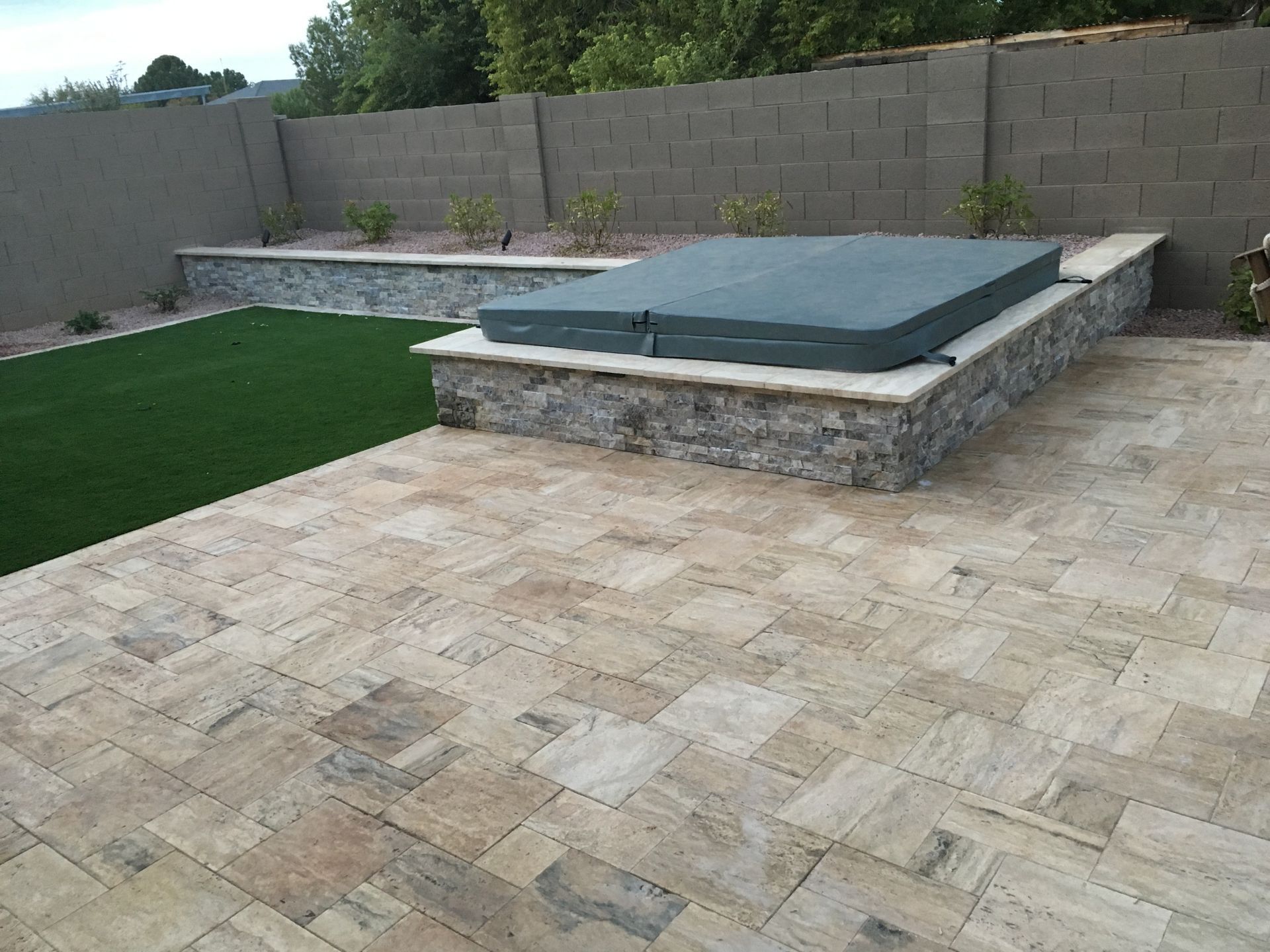 A hot tub is sitting on top of a stone wall on a patio.