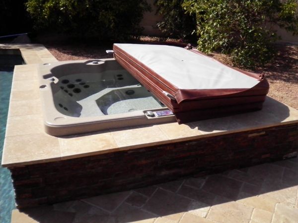 A hot tub with a cover on it sits next to a pool