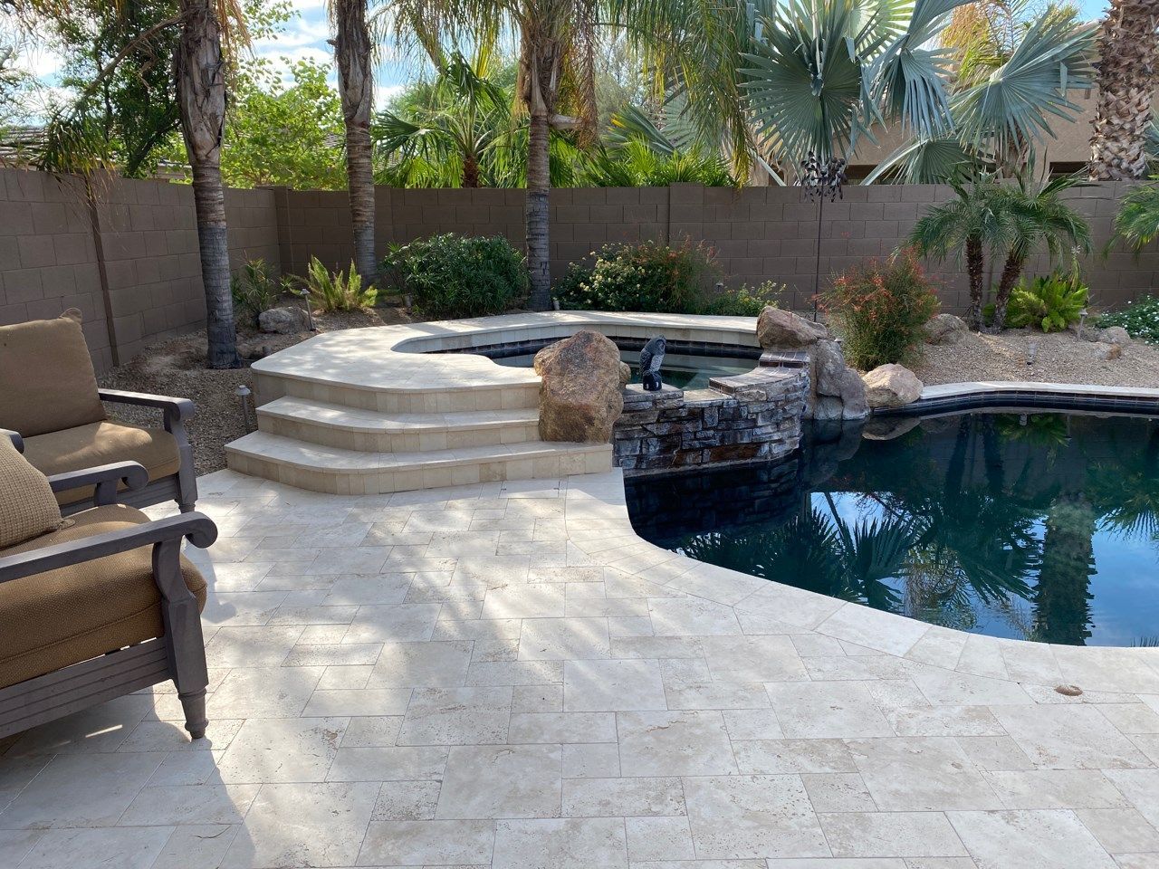 A patio with chairs and a swimming pool in the background