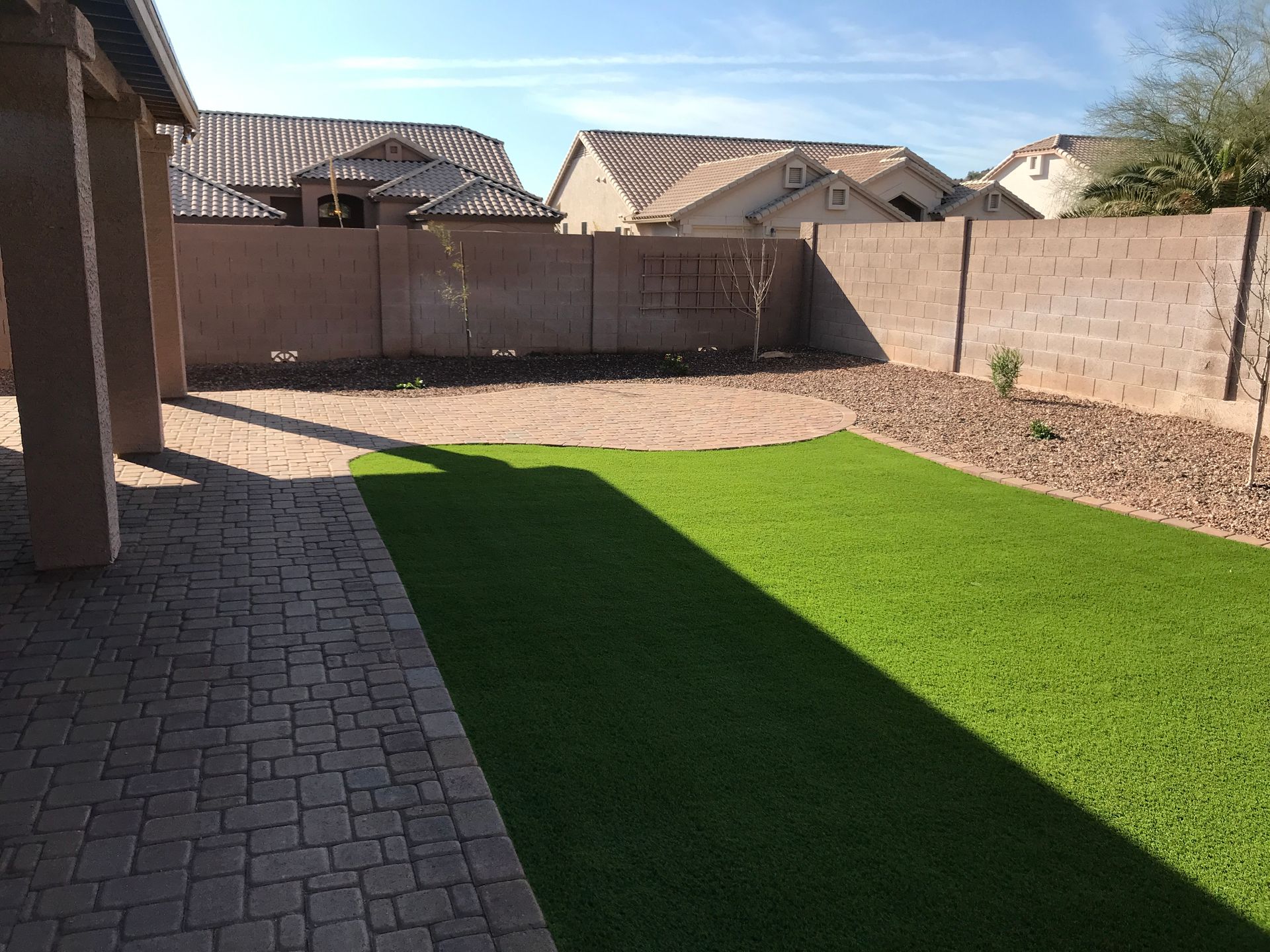 A backyard with a brick walkway and a lush green lawn.
