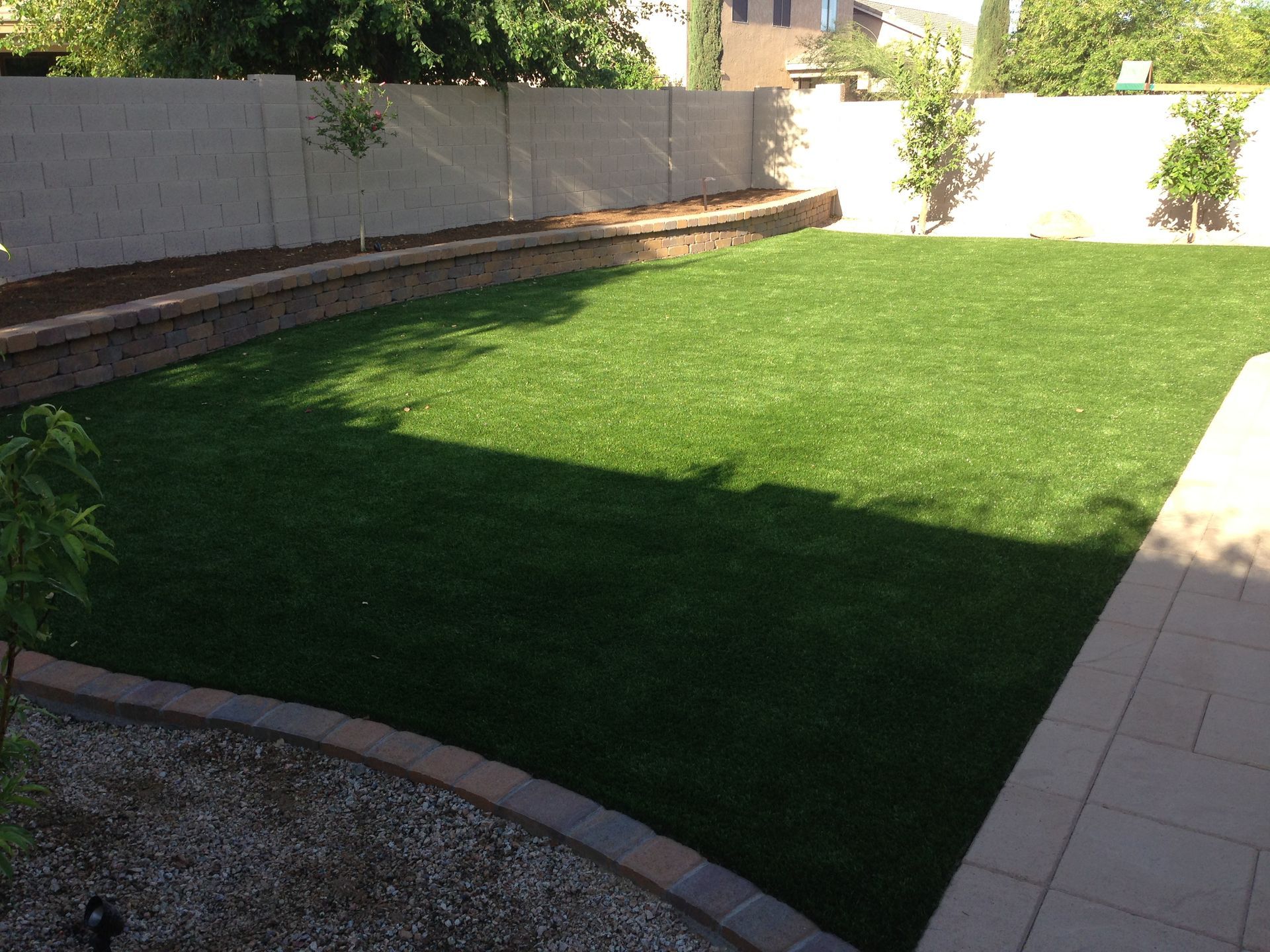 A backyard with a fence and a lush green lawn