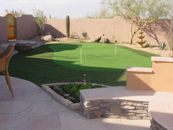 A backyard with a putting green in the middle
