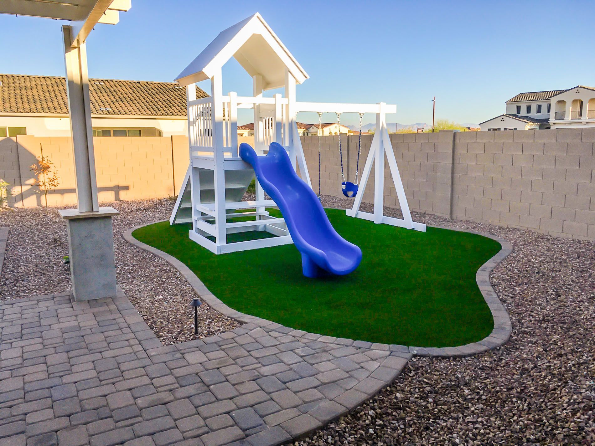 A backyard playground with a blue slide and swings