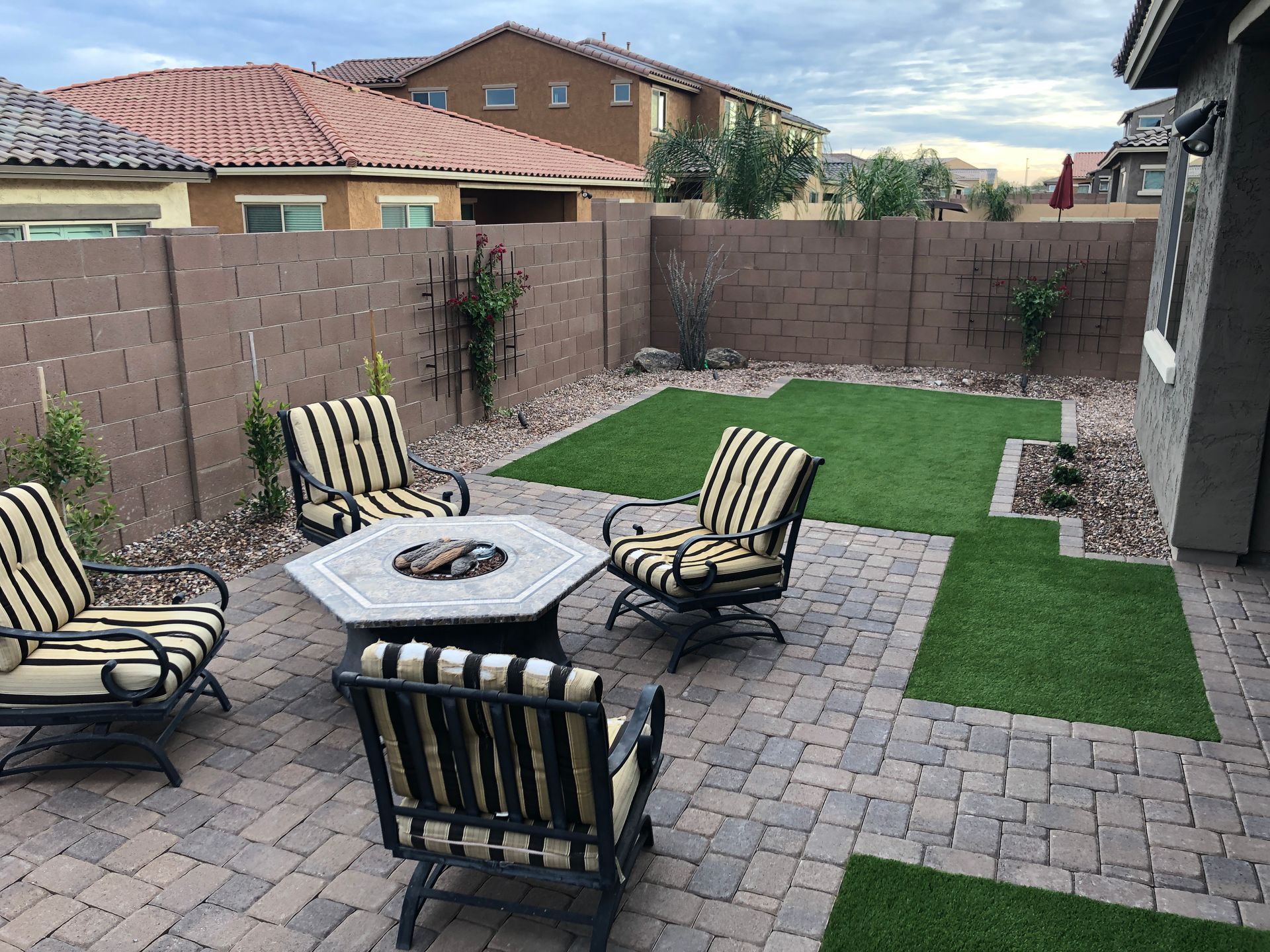 A patio with a fire pit , chairs and a table.