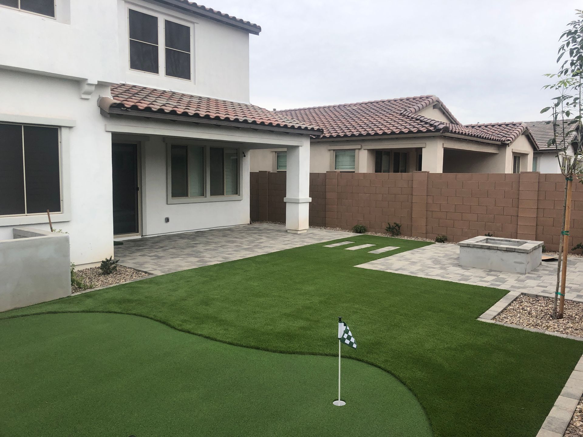 A backyard with a putting green and a fire pit