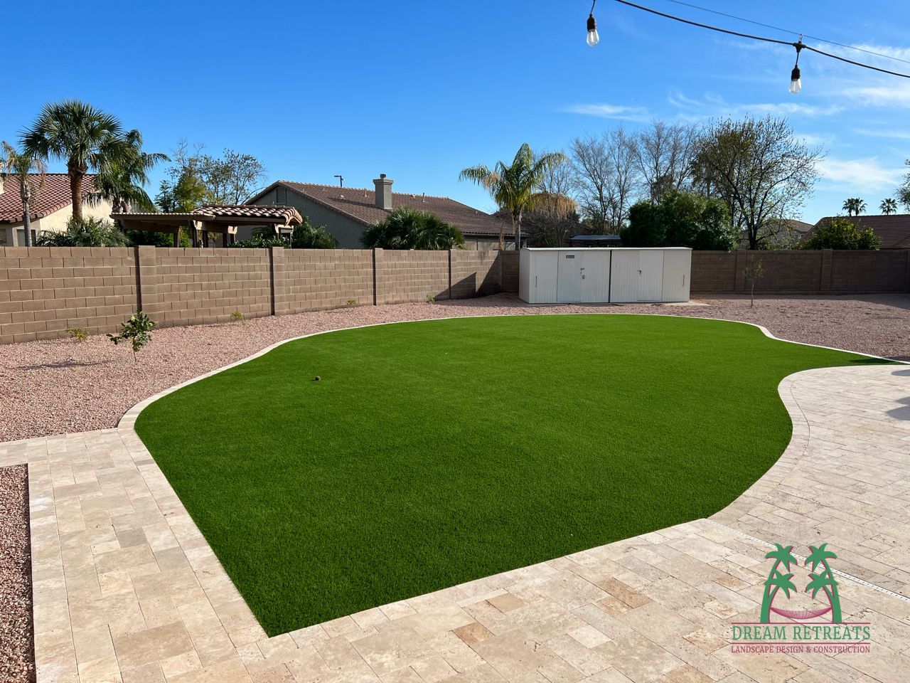 A backyard with a lot of green grass and a brick wall