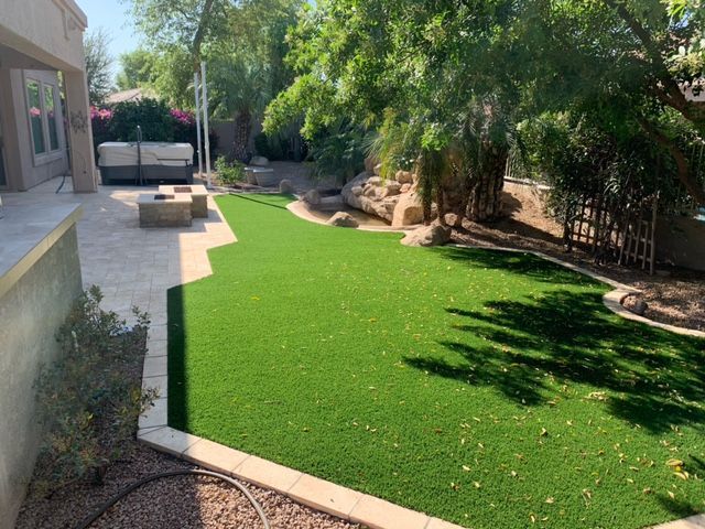 A backyard with a lush green lawn and a patio.