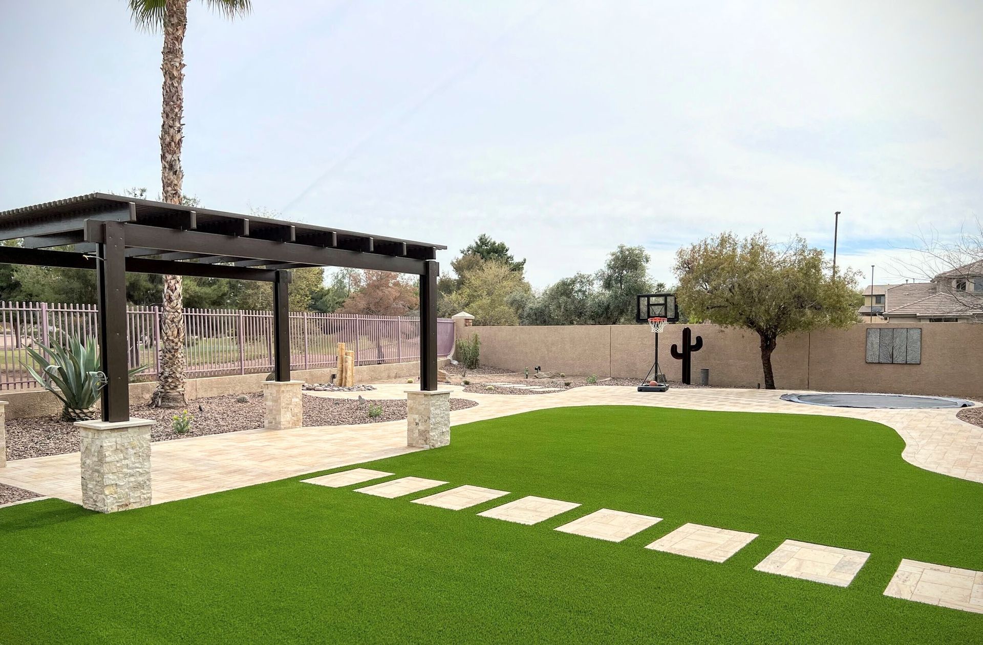 A backyard with a pergola and a basketball hoop.