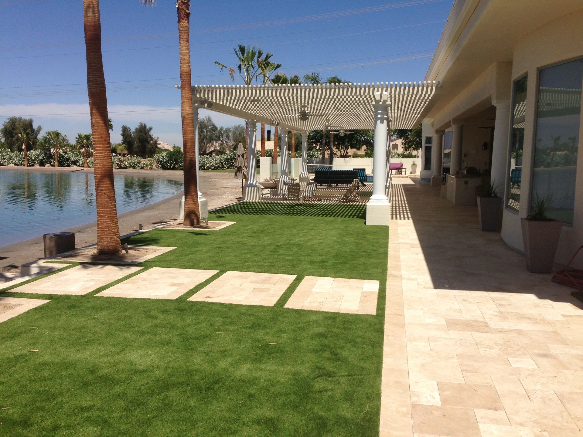 A large lawn with a pergola and a lake in the background