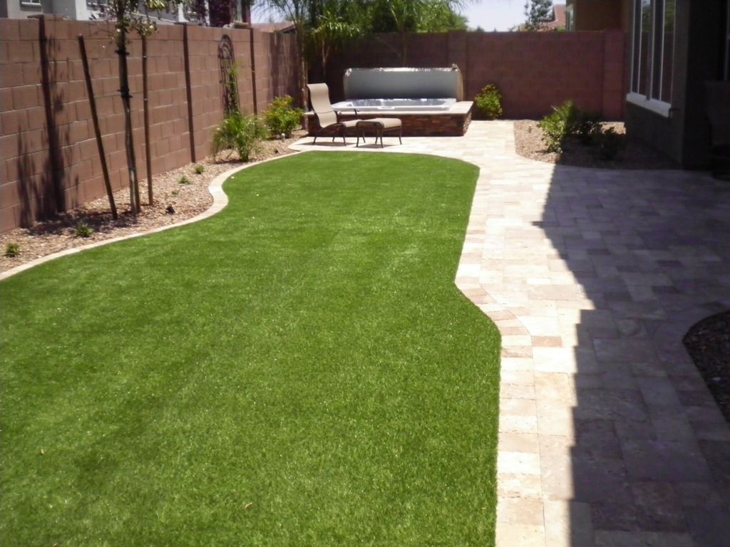 A backyard with a brick walkway and a hot tub