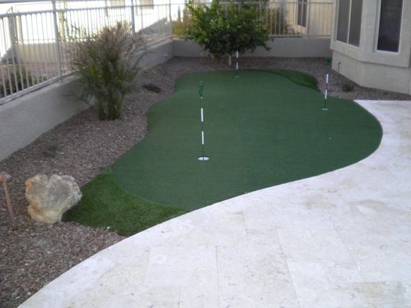 A small green putting green in a backyard
