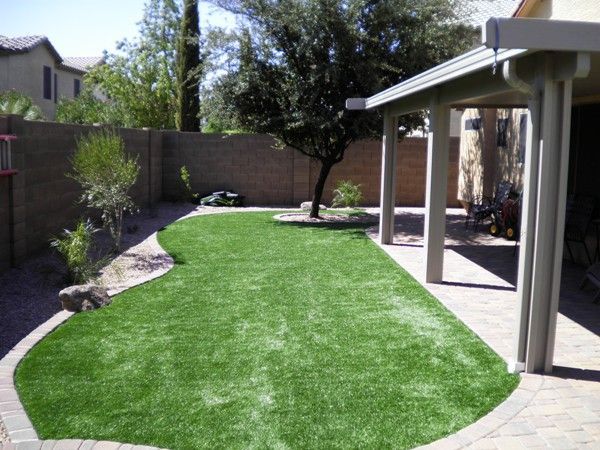 A backyard with a pergola and a lush green lawn