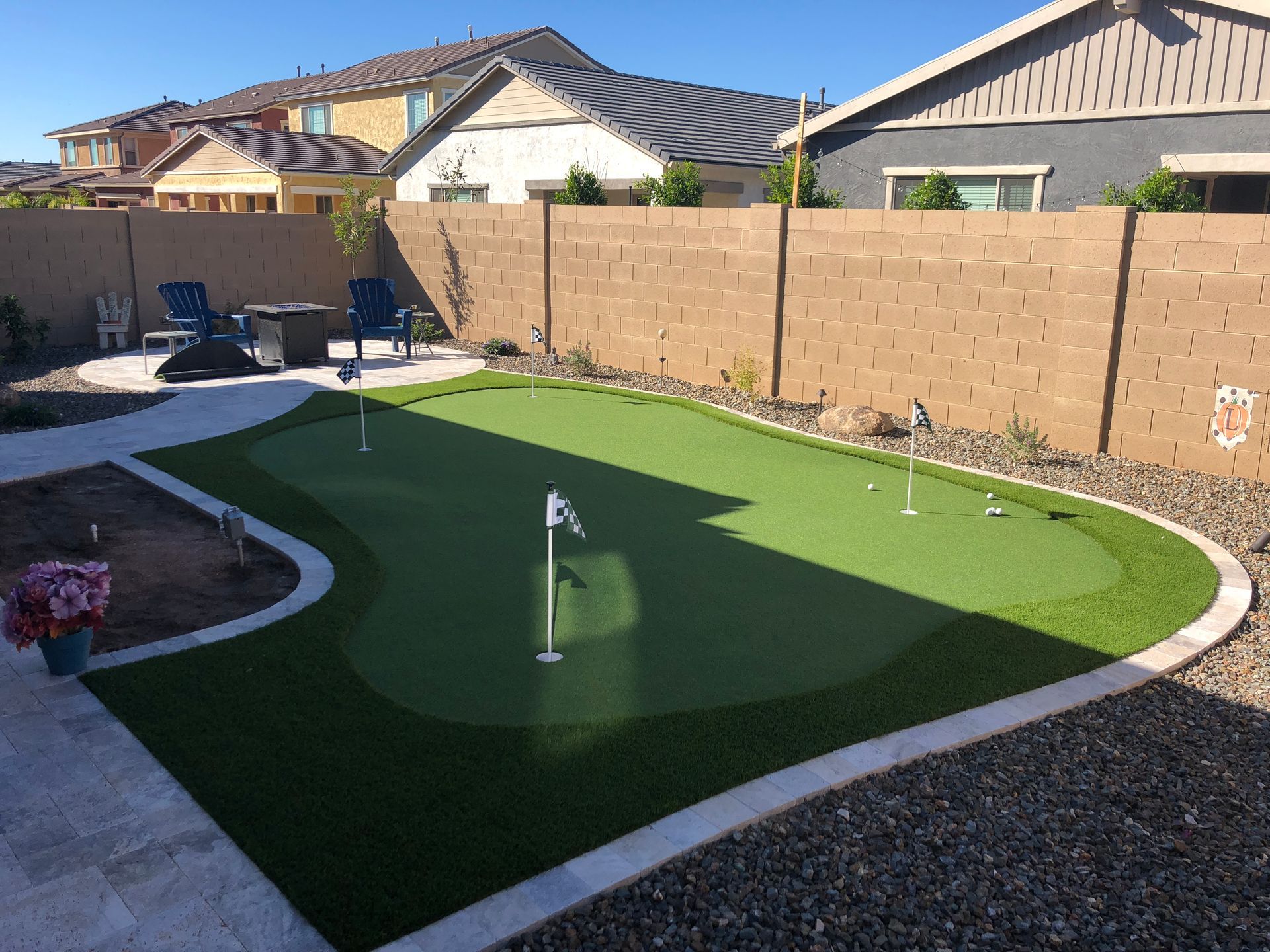 A backyard with a putting green and a fence