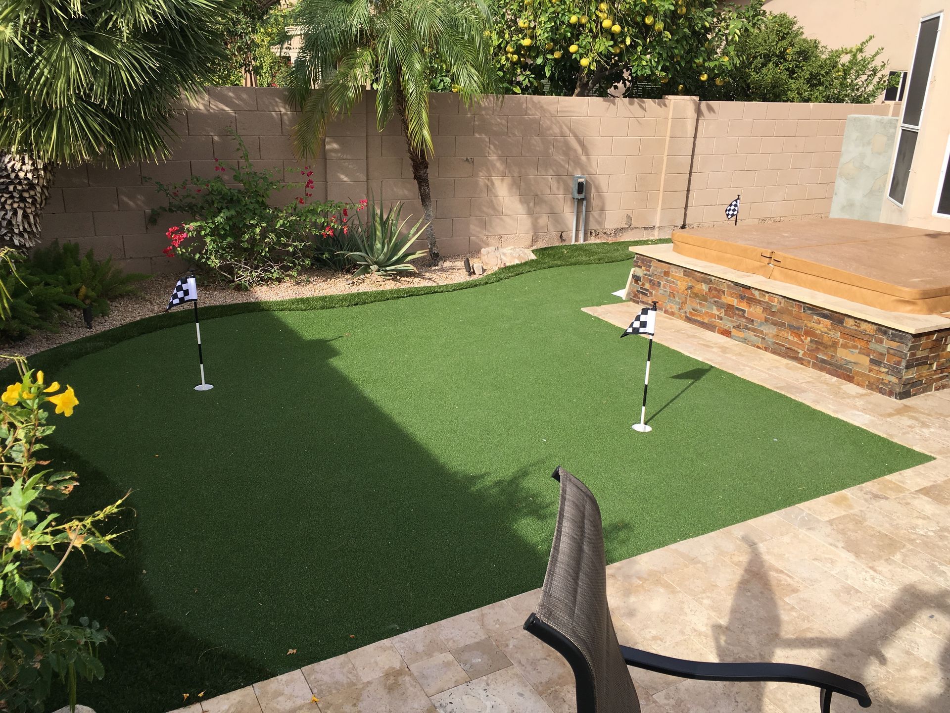 There is a putting green in the backyard of a house.