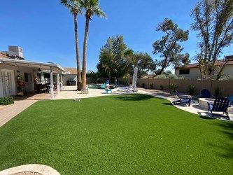 A large backyard with a lush green lawn and a swimming pool.