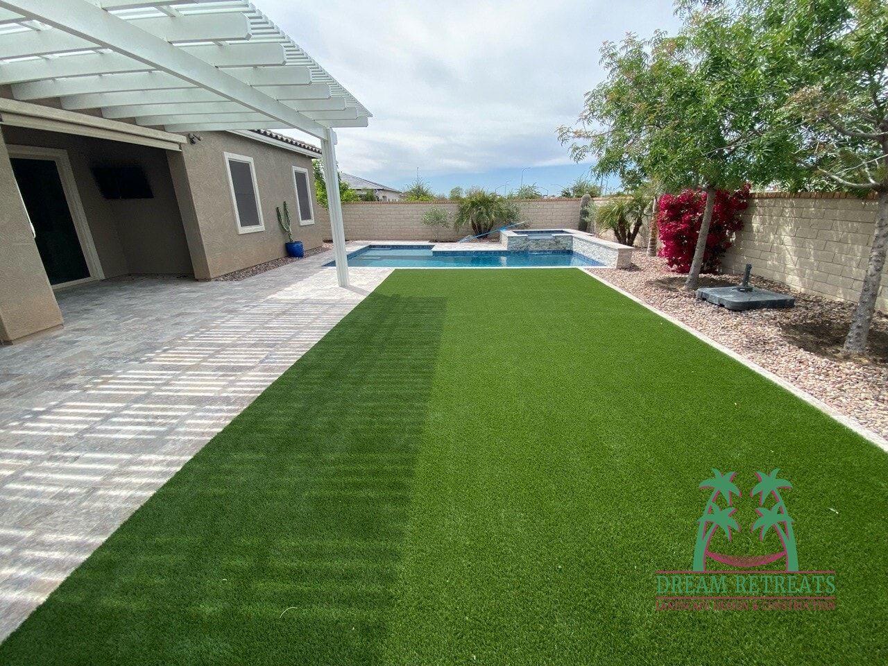 A backyard with a large lawn and a pool.