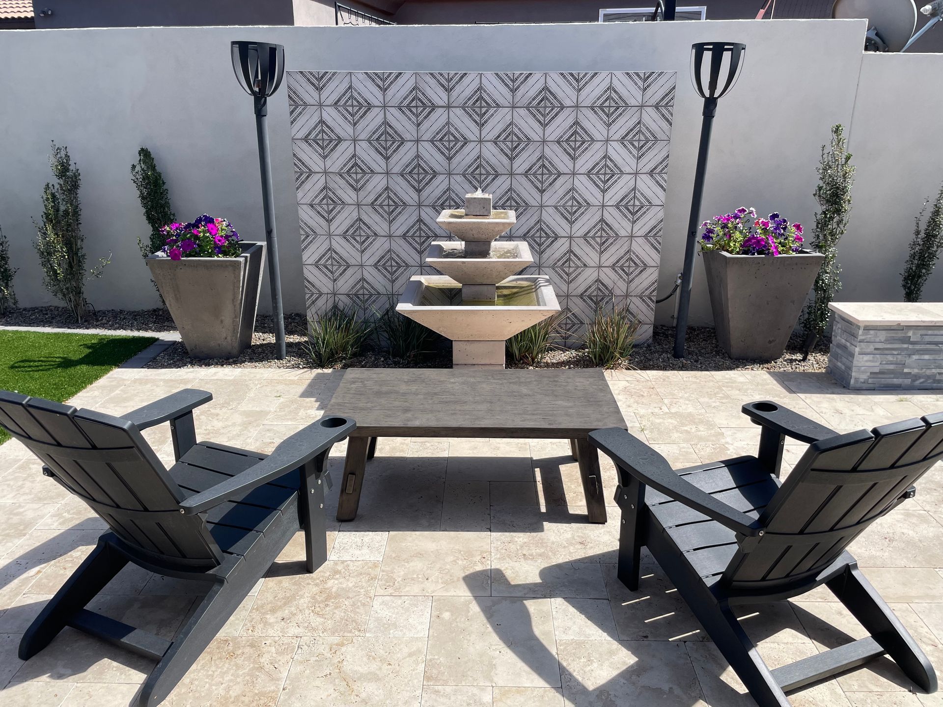 A patio with two chairs and a table with a fountain in the background