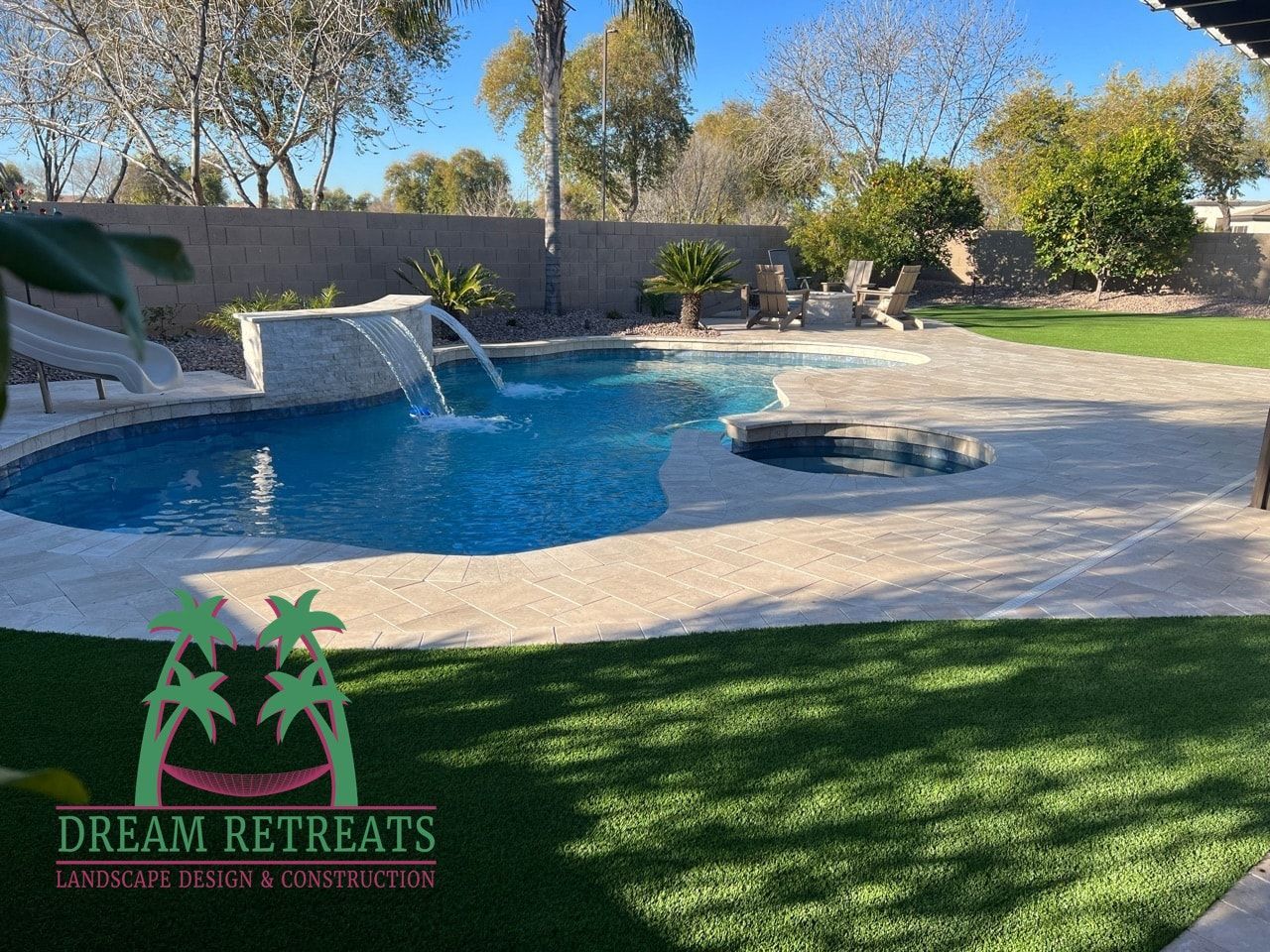A large swimming pool with a waterfall in the backyard.