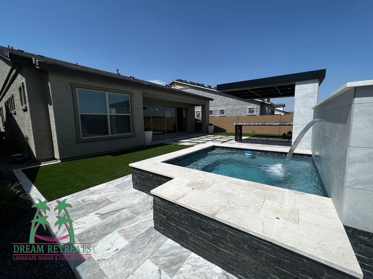 A swimming pool with a fountain in the backyard of a house.