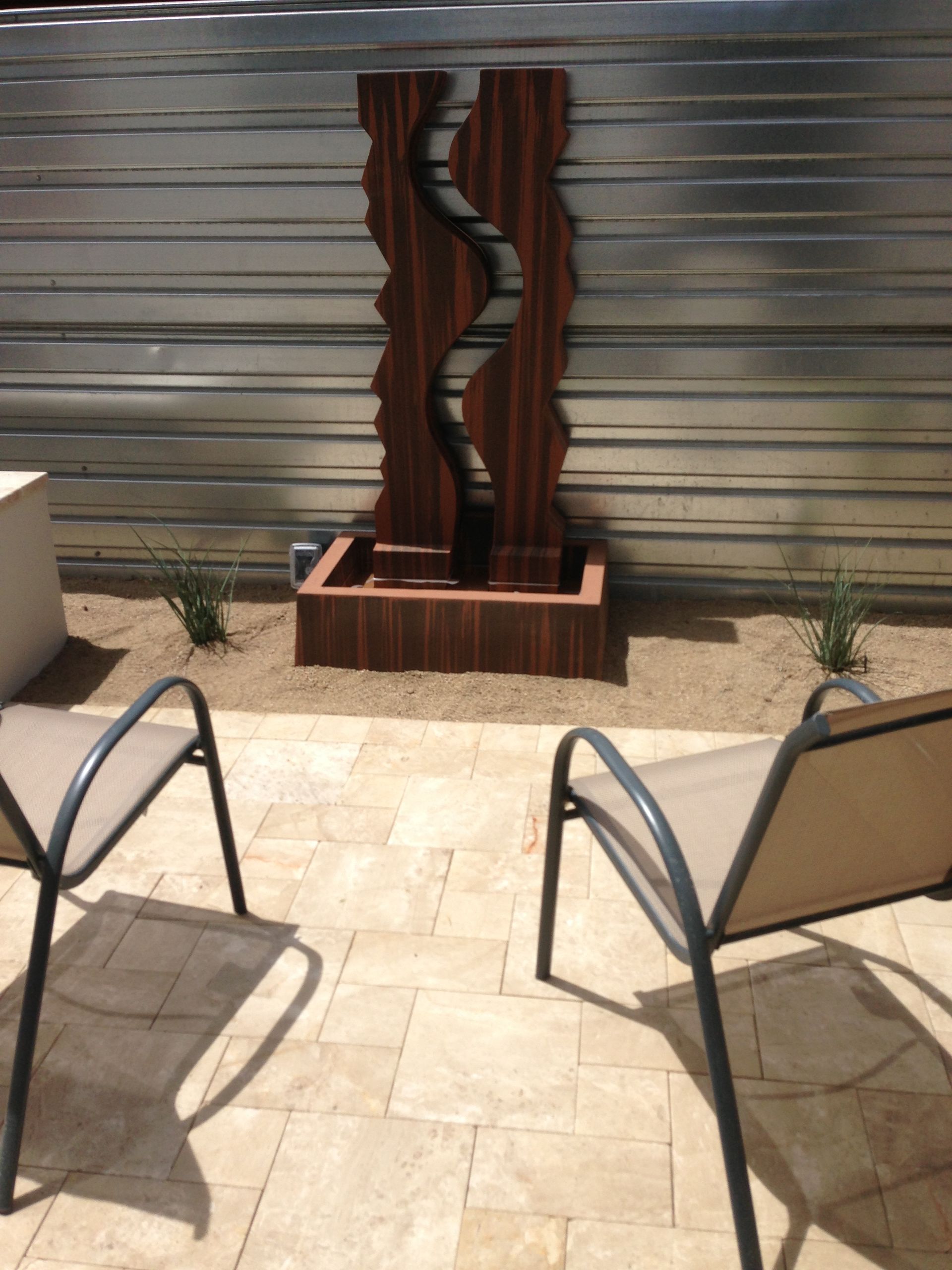 A patio with chairs and a fountain in the background