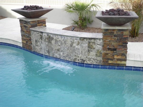 A swimming pool with a waterfall and a fire pit