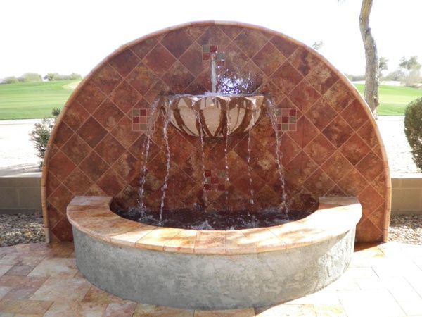 A fountain with water coming out of it in front of a golf course