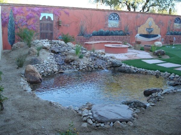 A pond surrounded by rocks and a fountain in a backyard