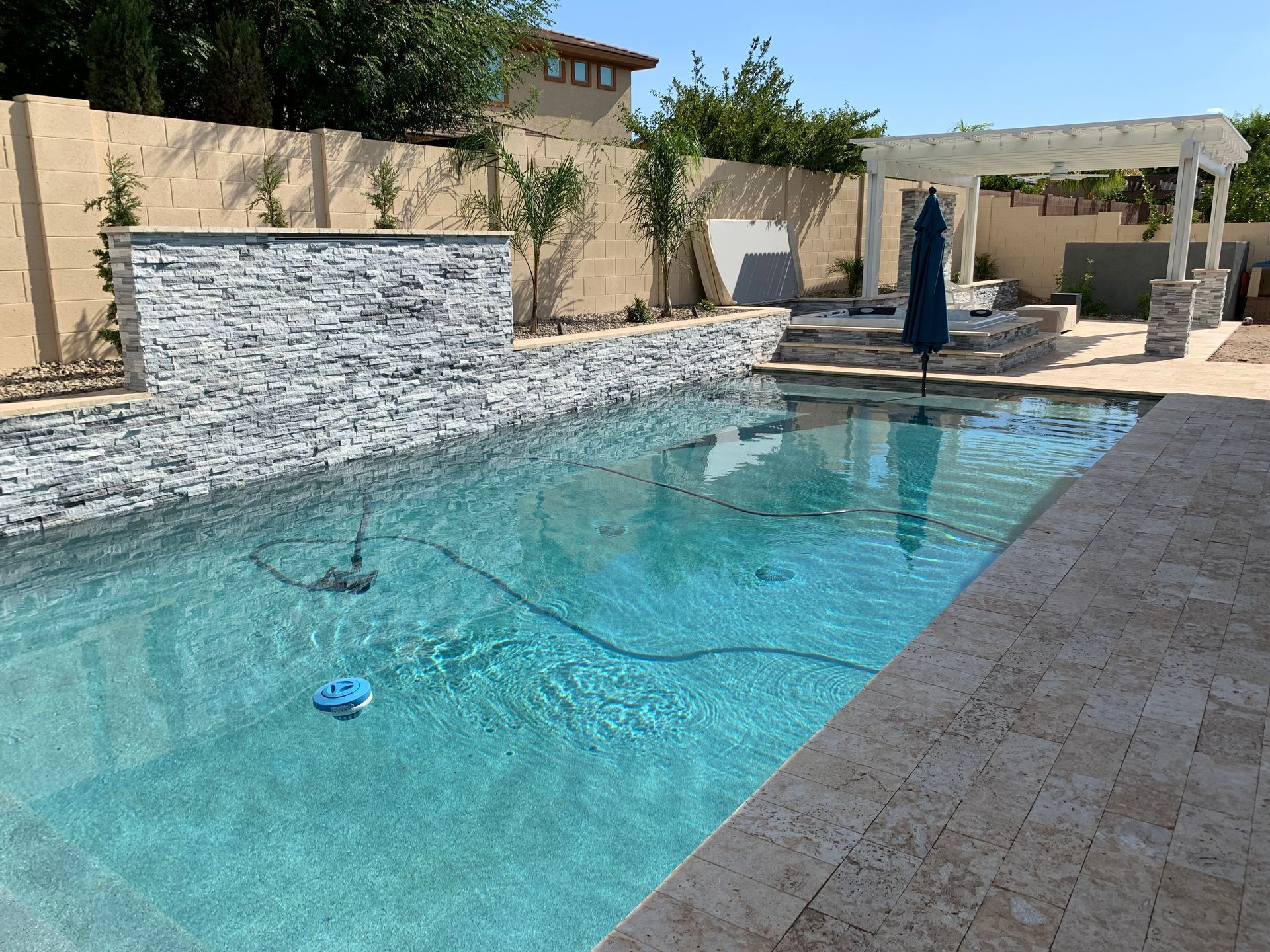 A large swimming pool with a waterfall in the backyard