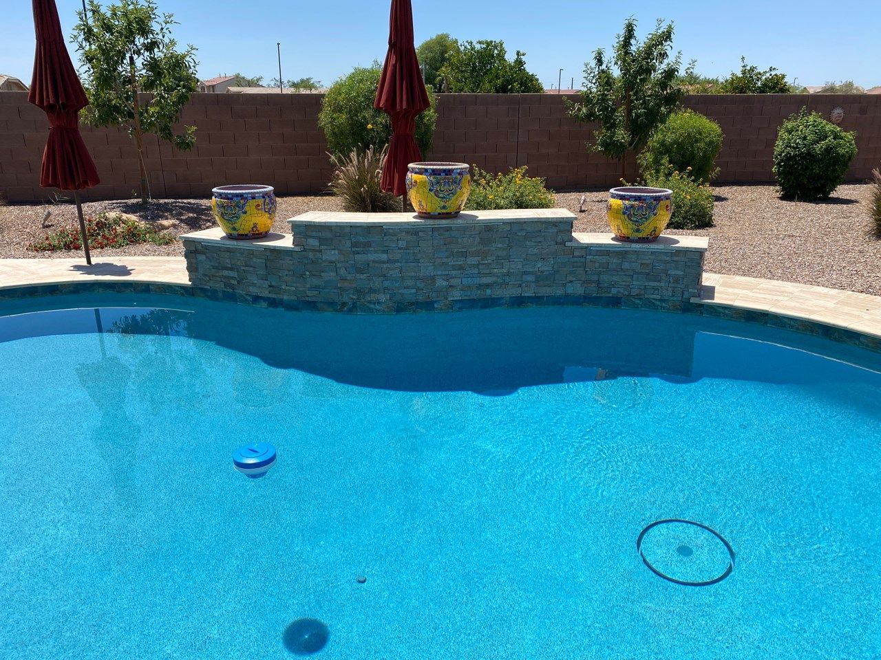 A swimming pool with three pots on the edge of it.