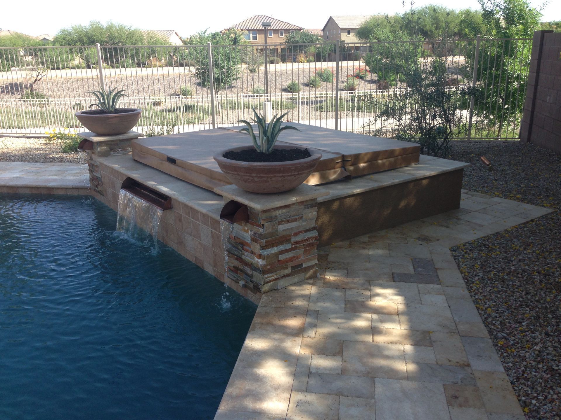 A swimming pool with a hot tub and a waterfall