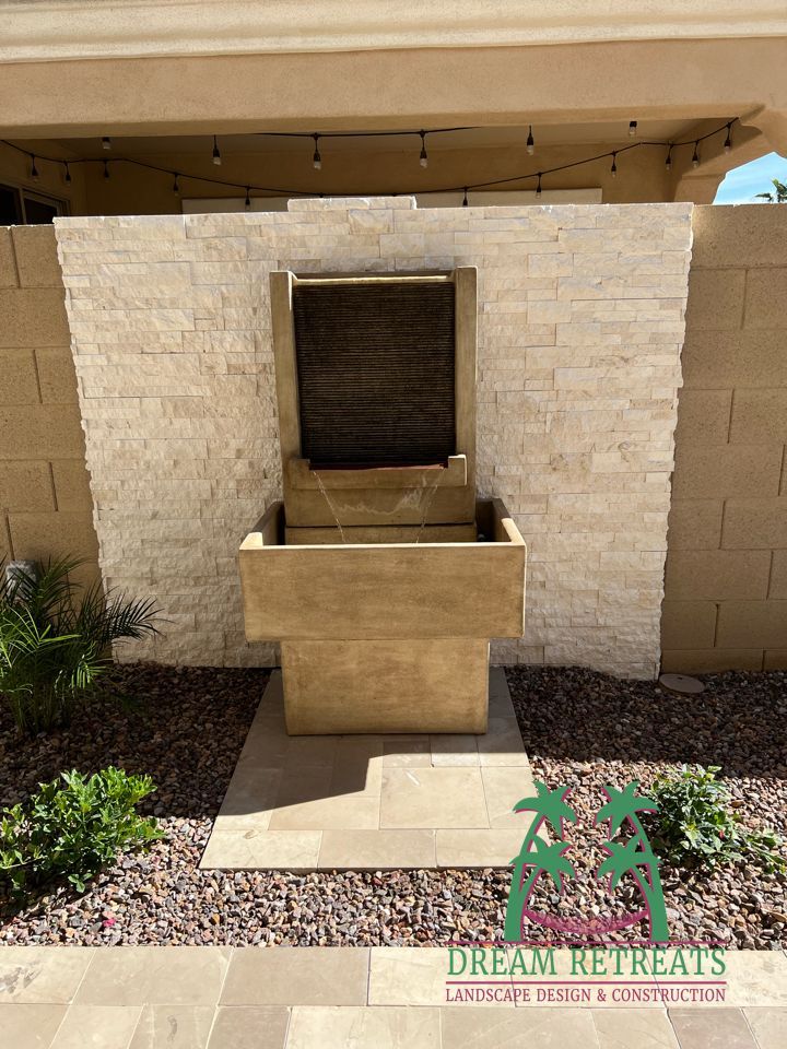 A water fountain is sitting in front of a brick wall.
