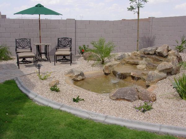 A backyard with a pond and chairs and an umbrella