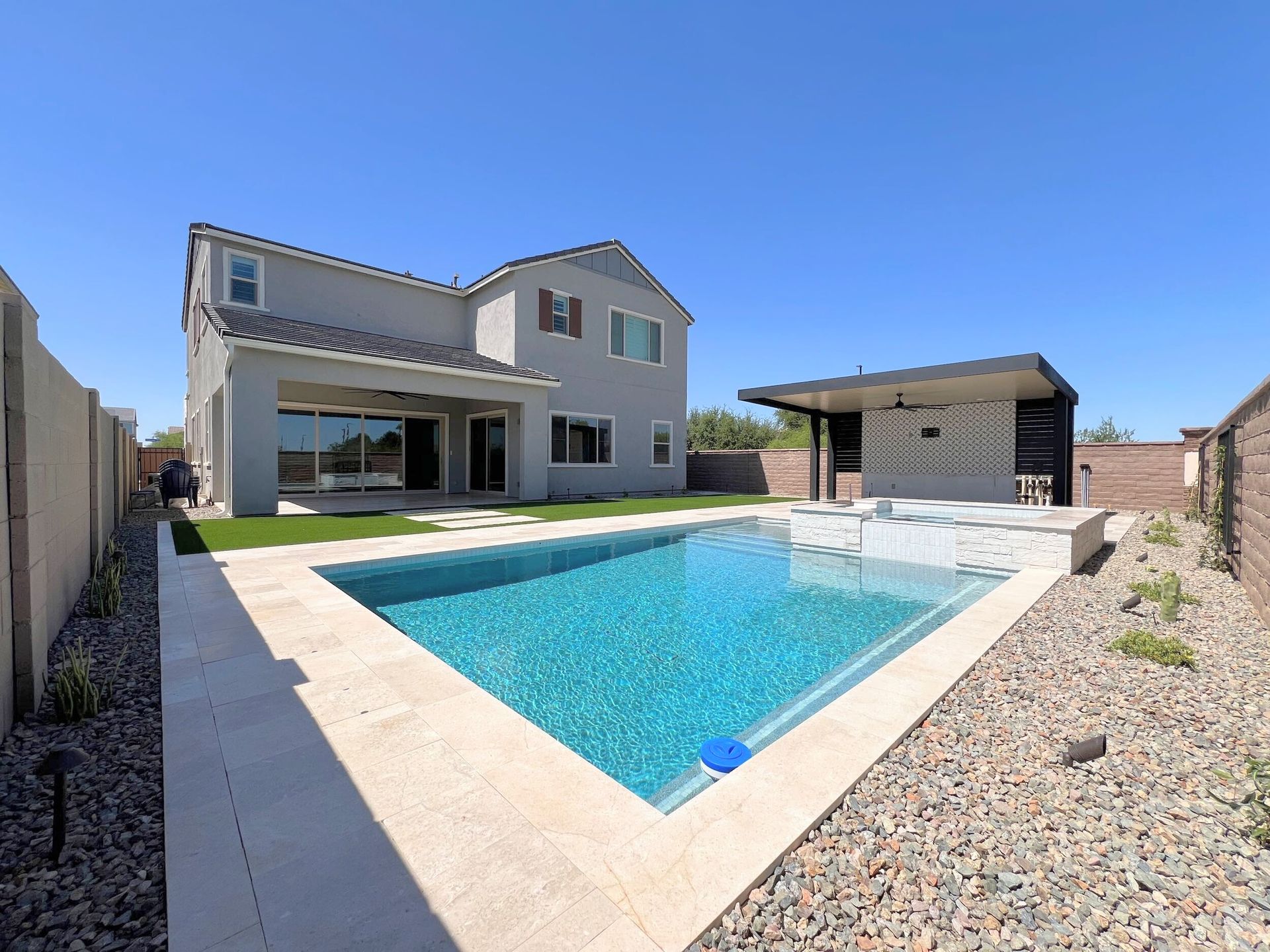 A large swimming pool is in the backyard of a house.