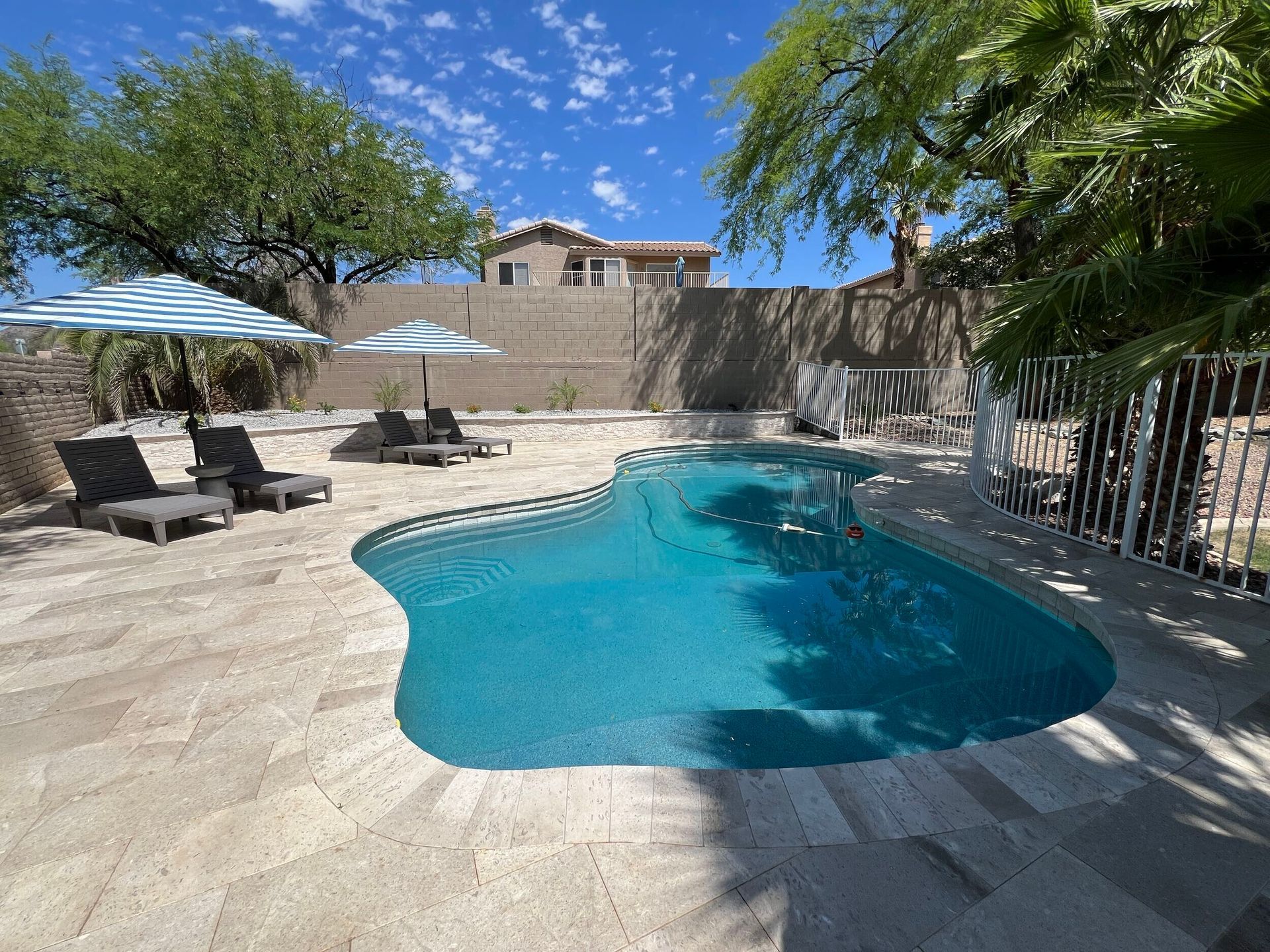 A large swimming pool is surrounded by chairs and umbrellas.