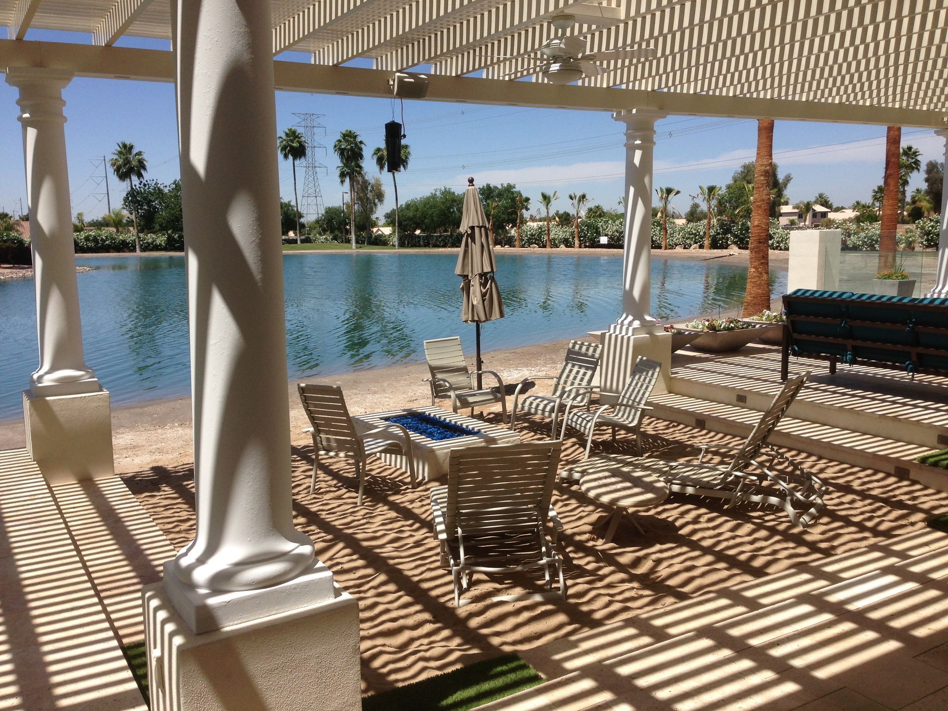 A pergola overlooking a lake with chairs and tables