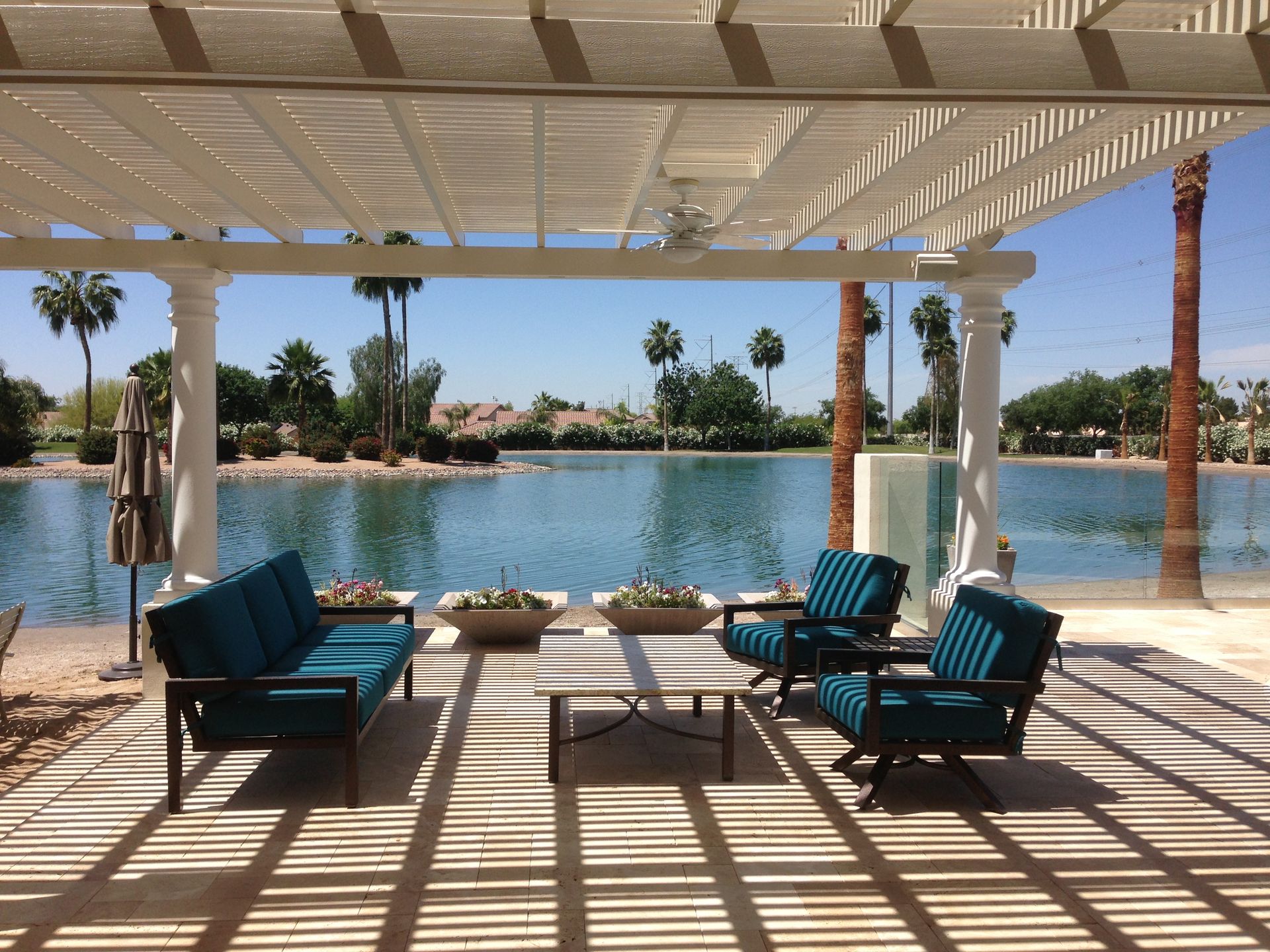 A pergola overlooking a lake with a couch and chairs