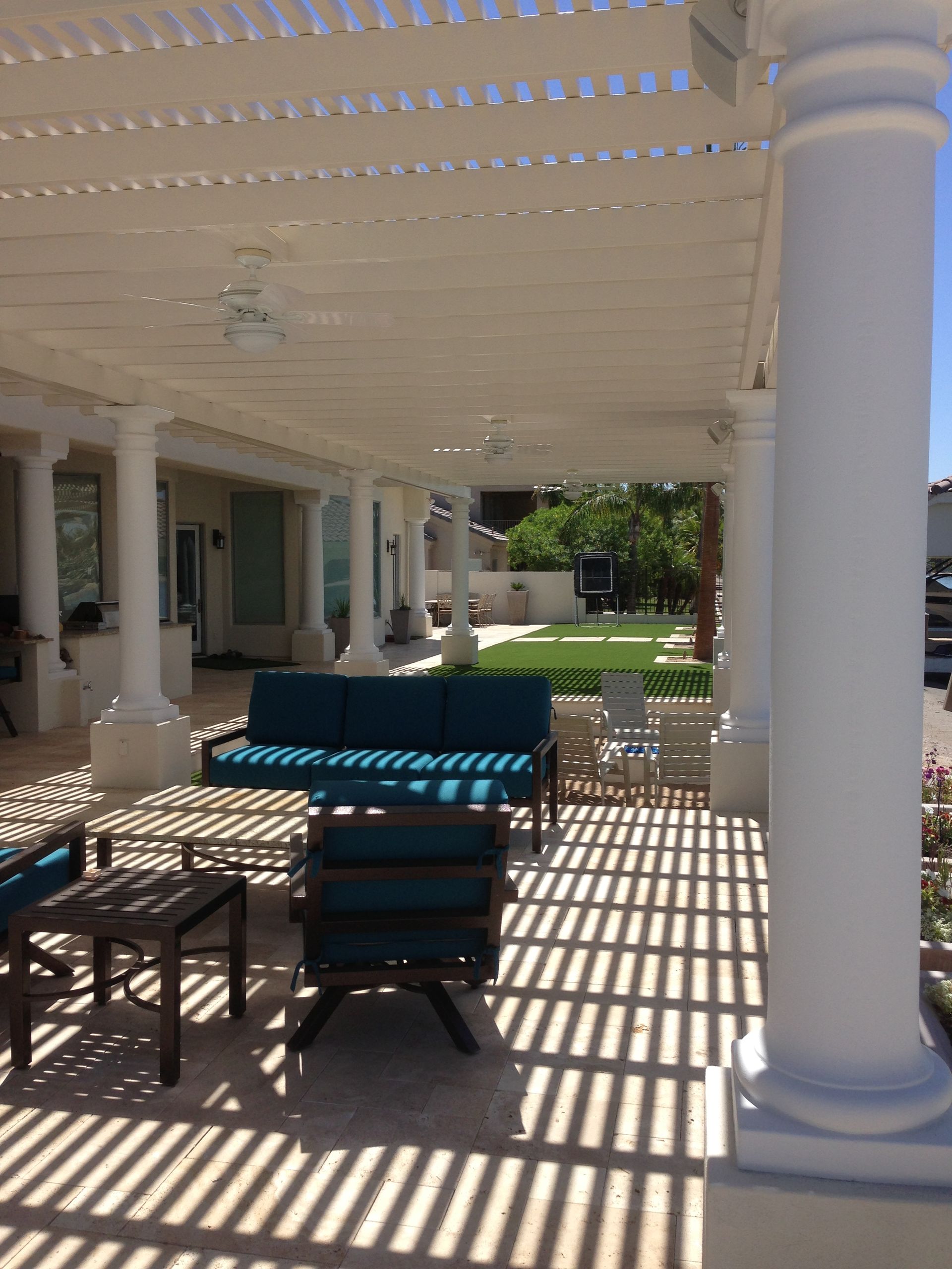 A porch with a couch and chairs under a pergola