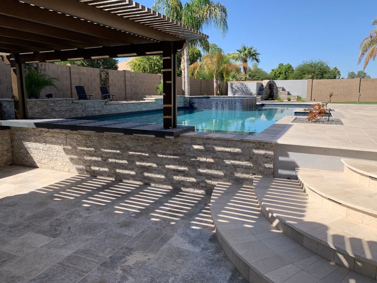 A large swimming pool with a pergola over it
