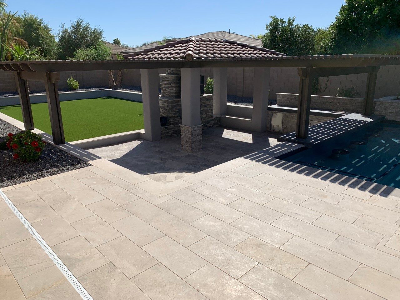 A patio with a gazebo and a pool in the background