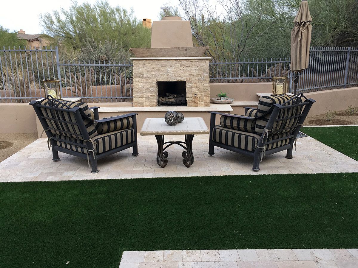 A patio with chairs and a fireplace in the backyard