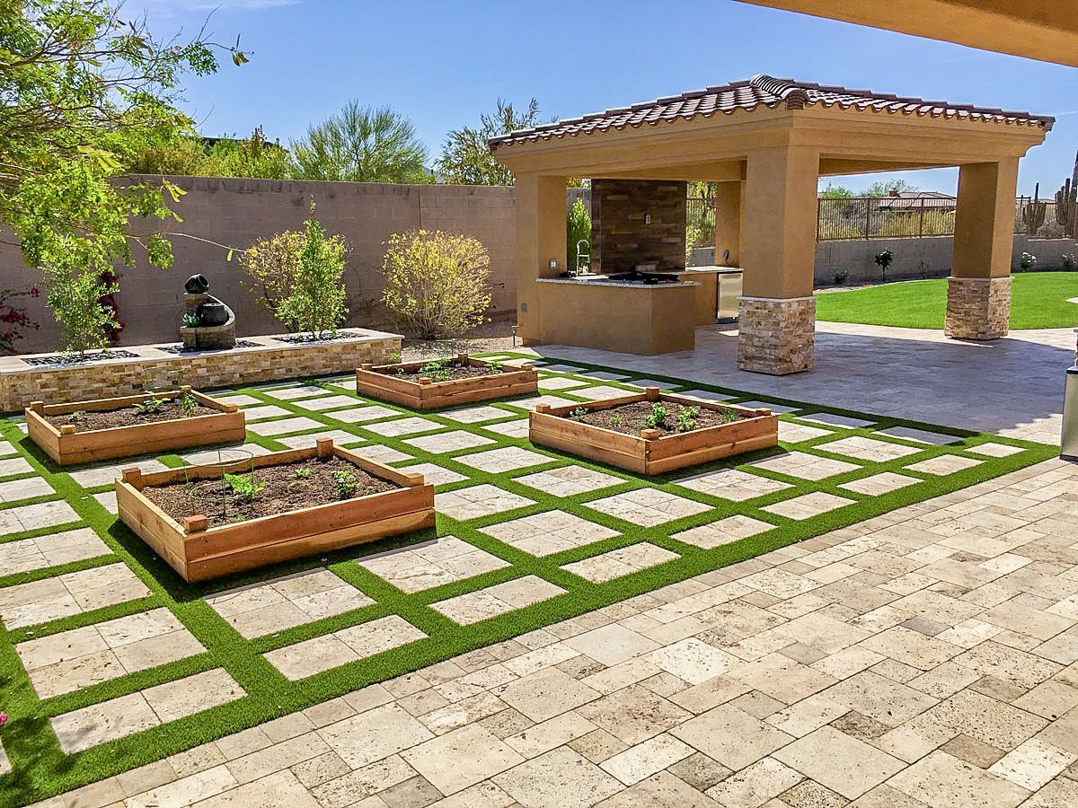 A patio with a gazebo and planters on the grass.