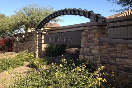 A stone wall with a sign that says quail creek