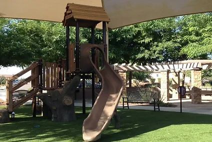 A playground with a slide and a tower in a park.