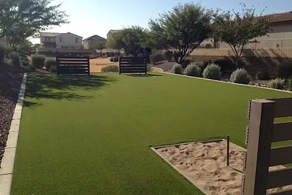 A lush green lawn with a sandbox in the middle of it.