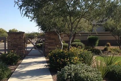 A walkway leading to a house with trees and bushes
