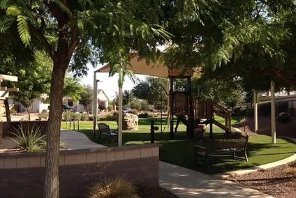 A park with a playground and benches under a canopy