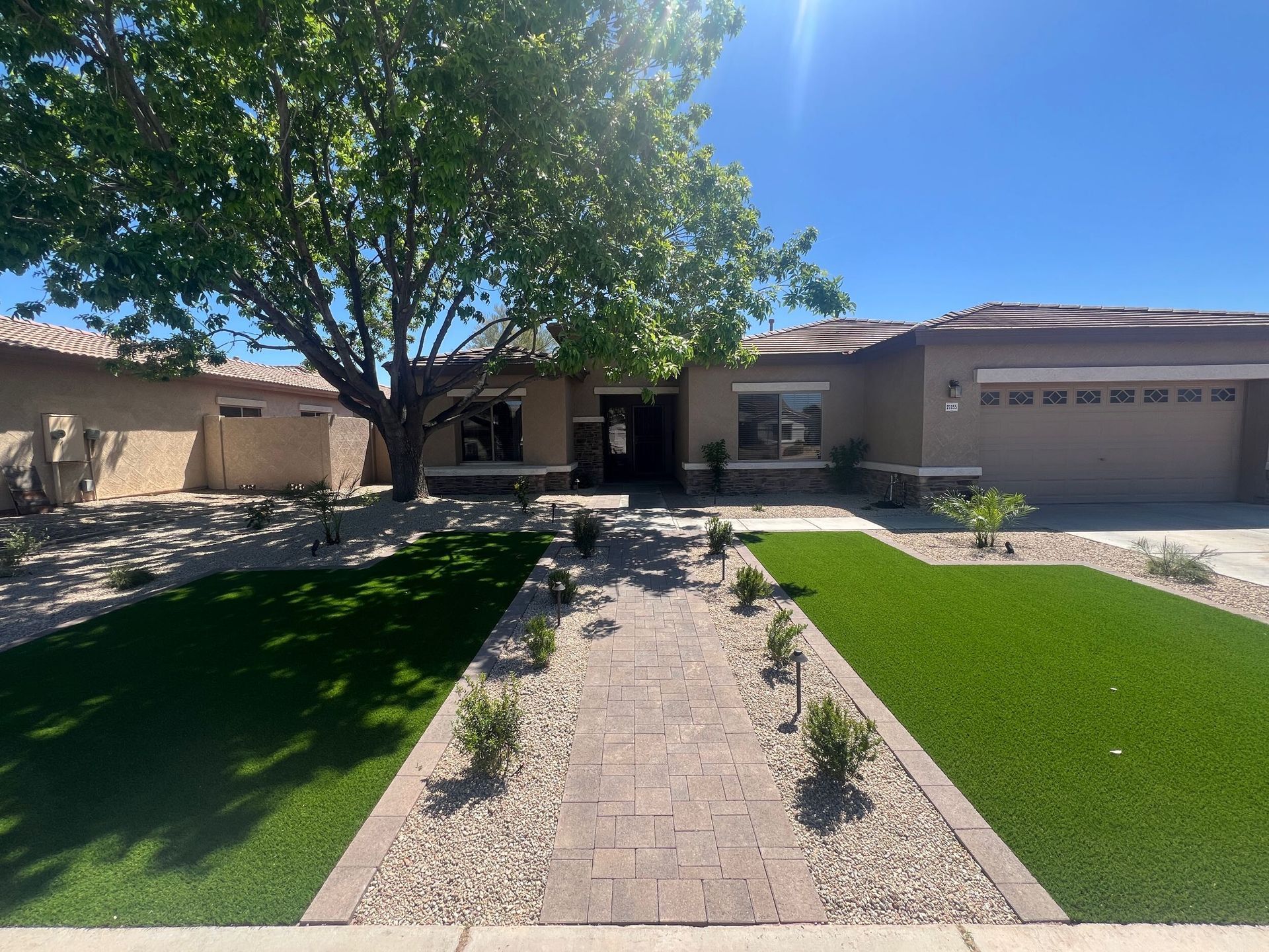 A house with a tree in front of it and a walkway leading to it.