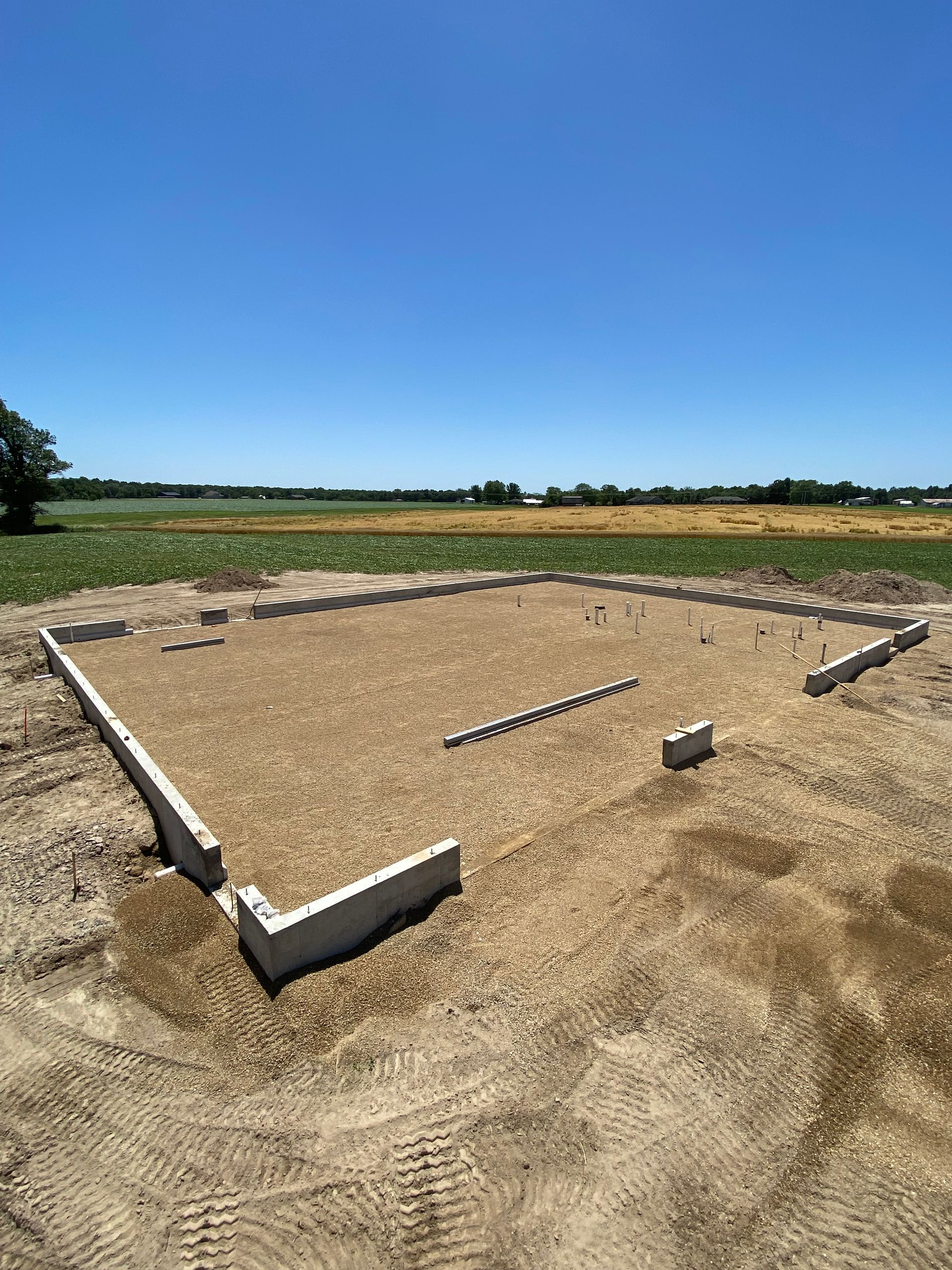A concrete foundation is being built in a dirt field.